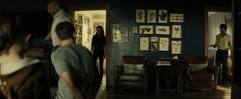 Movie still from “Knock at the Cabin” (2023), directed by M. Night Shyamalan – A woman standing in front of a door in a living room; Wide shot, Over the shoulder angle