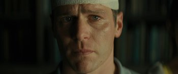 Movie still from “Knock at the Cabin” (2023), directed by M. Night Shyamalan – A person wearing a bandage on his head; Close Up shot, Low angle