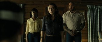 Movie still from “Knock at the Cabin” (2023), directed by M. Night Shyamalan – A group of people standing next to each other in a room; Medium shot, Low angle