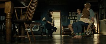 Movie still from “Knock at the Cabin” (2023), directed by M. Night Shyamalan – A woman holding a baseball bat while standing on the floor; Wide shot, Low angle