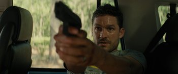 Movie still from “Knock at the Cabin” (2023), directed by M. Night Shyamalan – A person holding a gun in a car; Close Up shot, Over the shoulder angle