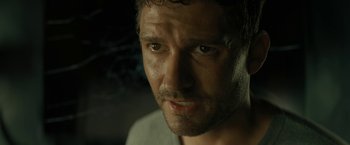 Movie still from “Knock at the Cabin” (2023), directed by M. Night Shyamalan – A man's face in a dimly - lit room; Close Up shot, Over the shoulder angle