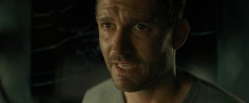 Movie still from “Knock at the Cabin” (2023), directed by M. Night Shyamalan – A man's face in a dimly - lit room; Close Up shot, Over the shoulder angle