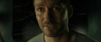 Movie still from “Knock at the Cabin” (2023), directed by M. Night Shyamalan – A man's face in a dimly - lit room; Close Up shot, Low angle