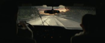 Movie still from “Knock at the Cabin” (2023), directed by M. Night Shyamalan – A view from a car of a road with a sunset in the background; Close Up shot, Over the shoulder angle