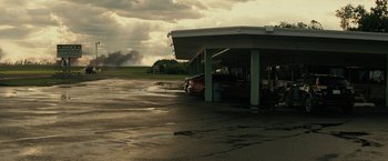 Movie still from “Knock at the Cabin” (2023), directed by M. Night Shyamalan – Cars parked in a parking lot under an awning; Extreme Wide shot, Low angle