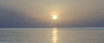 Movie still from “Kon-Tiki” (2012), directed by Espen Sandberg – The sun is setting over the ocean on a cloudy day; Extreme Wide shot, Low angle