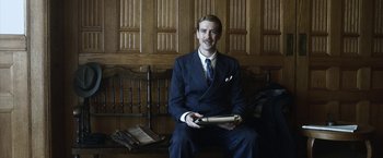 Movie still from “Kon-Tiki” (2012), directed by Espen Sandberg – A man in a suit and tie holding a book; Medium shot, Low angle
