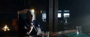 Movie still from “Kon-Tiki” (2012), directed by Espen Sandberg – An older man sitting at a table with a glass of water; Medium shot, Over the shoulder angle