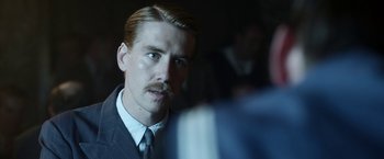 Movie still from “Kon-Tiki” (2012), directed by Espen Sandberg – A person wearing a suit and a tie; Close Up shot, Over the shoulder angle