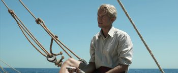 Movie still from “Kon-Tiki” (2012), directed by Espen Sandberg – A man sitting on the deck of a boat in the ocean; Medium shot, Low angle