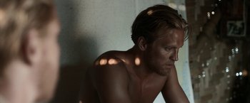 Movie still from “Kon-Tiki” (2012), directed by Espen Sandberg – A shirtless man sitting against a wall in the sunlight; Close Up shot, Low angle