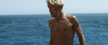 Movie still from “Kon-Tiki” (2012), directed by Espen Sandberg – A man with blond hair stands in front of the ocean; Medium shot, High angle