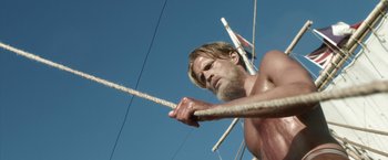 Movie still from “Kon-Tiki” (2012), directed by Espen Sandberg – A shirtless man holding a rope in the air; Medium shot, Low angle