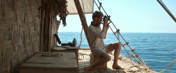 Movie still from “Kon-Tiki” (2012), directed by Espen Sandberg – A man sitting on a boat looking through binoculars; Medium shot, High angle