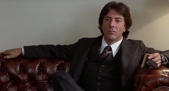 Movie still from “Kramer vs. Kramer” (1979), directed by Robert Benton – A man sitting on a couch wearing a suit and tie; Close Up shot, Low angle