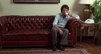 Movie still from “Kramer vs. Kramer” (1979), directed by Robert Benton – A man sitting on top of a brown leather couch; Wide shot, High angle