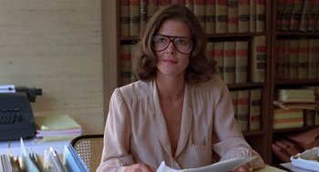 Movie still from “Kramer vs. Kramer” (1979), directed by Robert Benton – A woman sitting at a table in front of a book shelf; Medium shot, Low angle