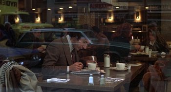 Movie still from “Kramer vs. Kramer” (1979), directed by Robert Benton – A man sitting at a table in front of a laptop; Medium shot, Over the shoulder angle