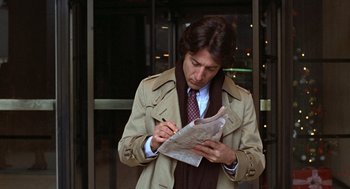 Movie still from “Kramer vs. Kramer” (1979), directed by Robert Benton – A man writing on a piece of paper in front of a building; Close Up shot, Over the shoulder angle
