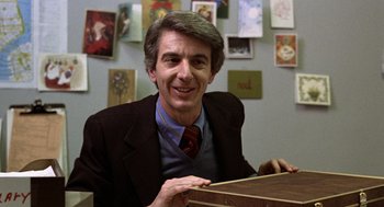 Movie still from “Kramer vs. Kramer” (1979), directed by Robert Benton – A man sitting at a table in front of pictures; Close Up shot, Over the shoulder angle