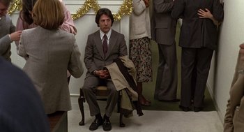 Movie still from “Kramer vs. Kramer” (1979), directed by Robert Benton – A man in a suit sitting on a chair in front of people; Wide shot, Low angle
