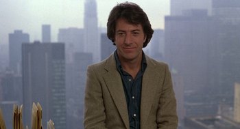 Movie still from “Kramer vs. Kramer” (1979), directed by Robert Benton – A man wearing a jacket and a shirt in front of a city skyline; Close Up shot, Low angle