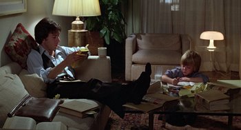 Movie still from “Kramer vs. Kramer” (1979), directed by Robert Benton – A man sitting on a couch next to a child; Medium shot, High angle