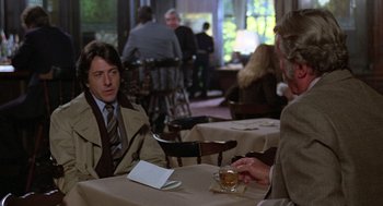 Movie still from “Kramer vs. Kramer” (1979), directed by Robert Benton – A man sitting at a table in a restaurant with another man; Medium shot, Over the shoulder angle