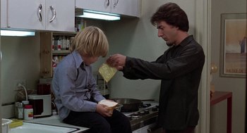 Movie still from “Kramer vs. Kramer” (1979), directed by Robert Benton – A man and a boy in a kitchen with a sandwich; Medium shot, Over the shoulder angle