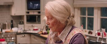Movie still from “Krampus” (2015), directed by Michael Dougherty – An older woman in a kitchen looking off to the side; Close Up shot, Over the shoulder angle