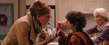 Movie still from “Krampus” (2015), directed by Michael Dougherty – A woman and a boy are putting something in their mouth; Close Up shot, Over the shoulder angle