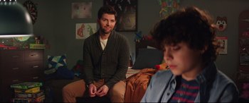 Movie still from “Krampus” (2015), directed by Michael Dougherty – A man sitting on a bed in front of another man; Medium shot, Over the shoulder angle