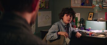 Movie still from “Krampus” (2015), directed by Michael Dougherty – A young boy sitting in a chair in front of a drawing; Close Up shot, Over the shoulder angle