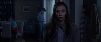 Movie still from “Krampus” (2015), directed by Michael Dougherty – A woman standing in front of a man in a dark room; Medium shot, Over the shoulder angle