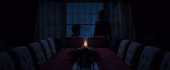 Movie still from “Krampus” (2015), directed by Michael Dougherty – A man and a woman sitting at a table with a lit candle; Wide shot, High angle