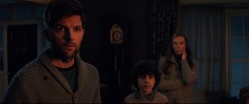 Movie still from “Krampus” (2015), directed by Michael Dougherty – A group of people standing next to each other in a dark room; Medium shot, Over the shoulder angle