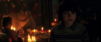 Movie still from “Krampus” (2015), directed by Michael Dougherty – A young boy standing in front of candles; Close Up shot, Over the shoulder angle