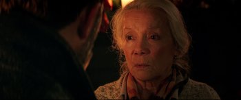Movie still from “Krampus” (2015), directed by Michael Dougherty – An older woman looking at the camera with a man in the background; Close Up shot, Over the shoulder angle