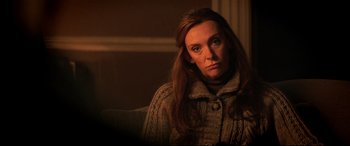 Movie still from “Krampus” (2015), directed by Michael Dougherty – A woman sitting on a couch in a room; Close Up shot, Over the shoulder angle