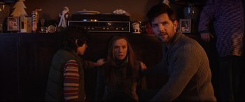 Movie still from “Krampus” (2015), directed by Michael Dougherty – A man and a woman and a boy in front of a television; Medium shot, Over the shoulder angle