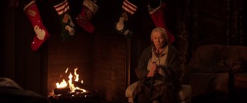 Movie still from “Krampus” (2015), directed by Michael Dougherty – An older woman sitting in front of a fireplace; Medium shot, Low angle