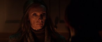Movie still from “Krampus” (2015), directed by Michael Dougherty – A woman stares at the camera while a man sits in the background; Close Up shot, Over the shoulder angle