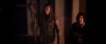 Movie still from “Krampus” (2015), directed by Michael Dougherty – A woman holding an axe in a room; Medium shot, Over the shoulder angle