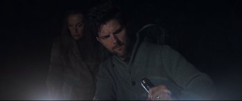 Movie still from “Krampus” (2015), directed by Michael Dougherty – A man holding a microphone in front of a woman in a dark room; Close Up shot, Over the shoulder angle