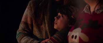 Movie still from “Krampus” (2015), directed by Michael Dougherty – A young boy looking up at the sky while holding a pillow; Close Up shot, Over the shoulder angle