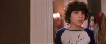 Movie still from “Krampus” (2015), directed by Michael Dougherty – A boy with curly hair is standing in a room; Close Up shot, Over the shoulder angle