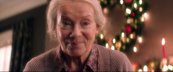 Movie still from “Krampus” (2015), directed by Michael Dougherty – An older woman with a smile on her face; Close Up shot, Over the shoulder angle