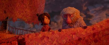 Movie still from “Kubo and the Two Strings” (2016), directed by Travis Knight – A monkey sitting next to a girl on a bed of leaves; Wide shot, Over the shoulder angle