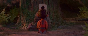 Movie still from “Kubo and the Two Strings” (2016), directed by Travis Knight – A person sitting on the ground in front of a tree; Wide shot, Low angle